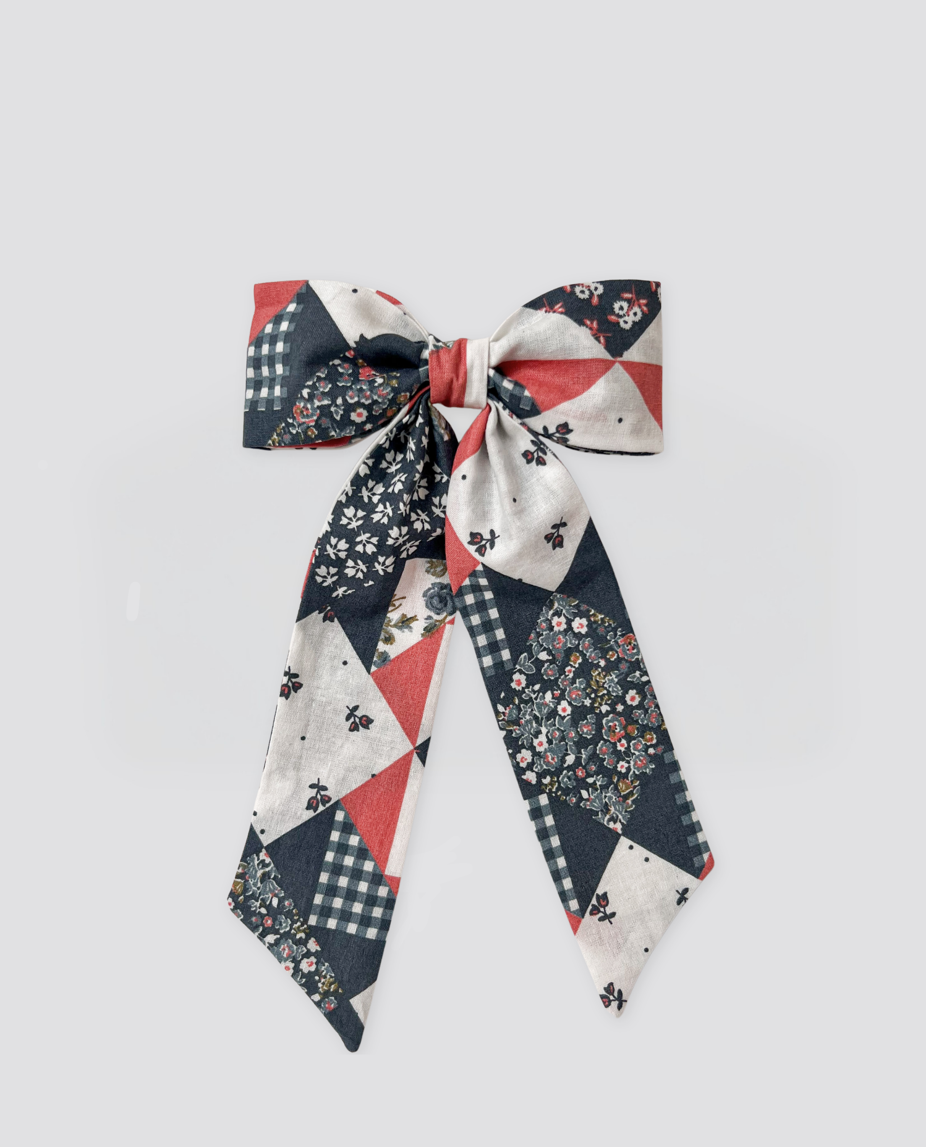 Handmade patchwork floral hair bow clip in vintage-inspired navy, soft red, and cream, crafted from natural cotton with a nostalgic, ethical children’s clothing style.