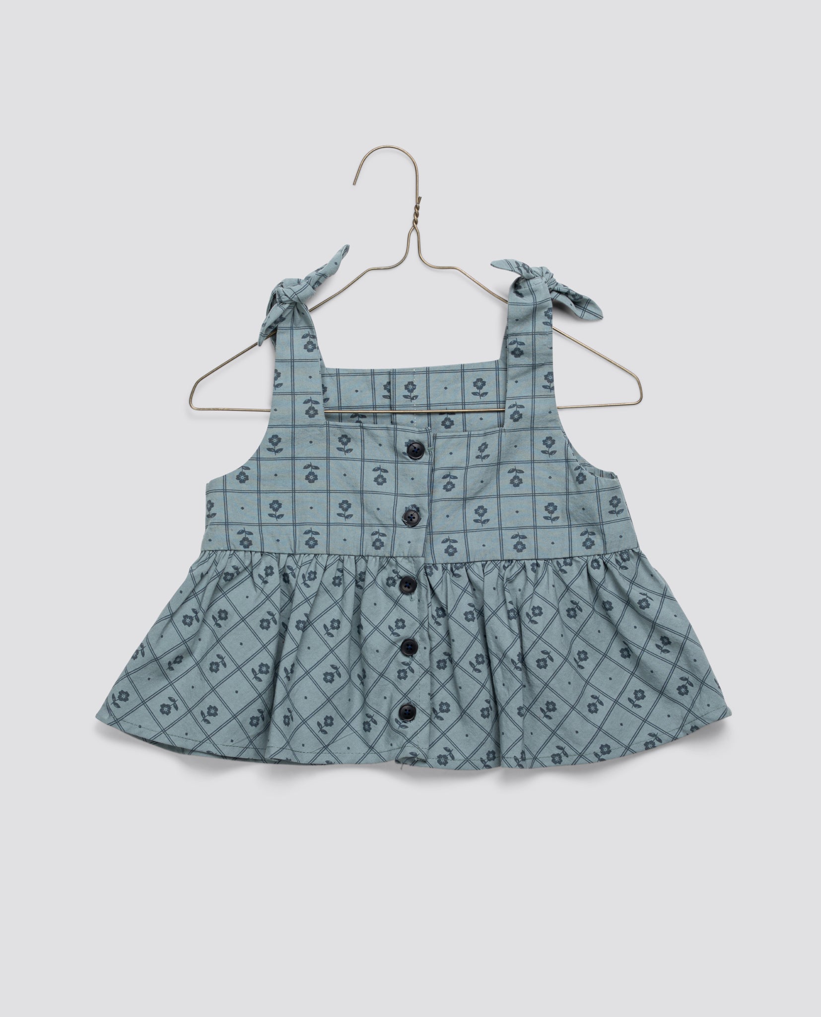 Light blue vintage style girls blouse made from organic cotton with floral pattern and button front, featuring tie shoulder straps for a sustainable, natural look.