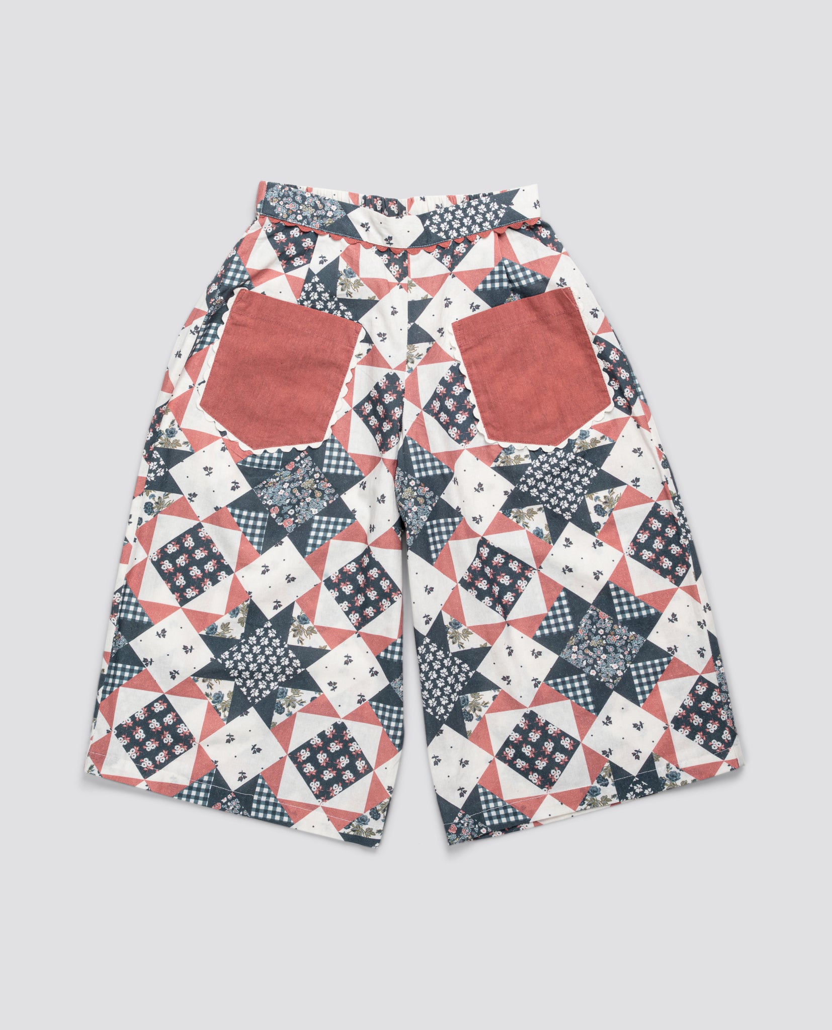 Vintage style children's patchwork trousers in floral blue and rust with large front pockets, made from organic cotton for a sustainable, natural look.