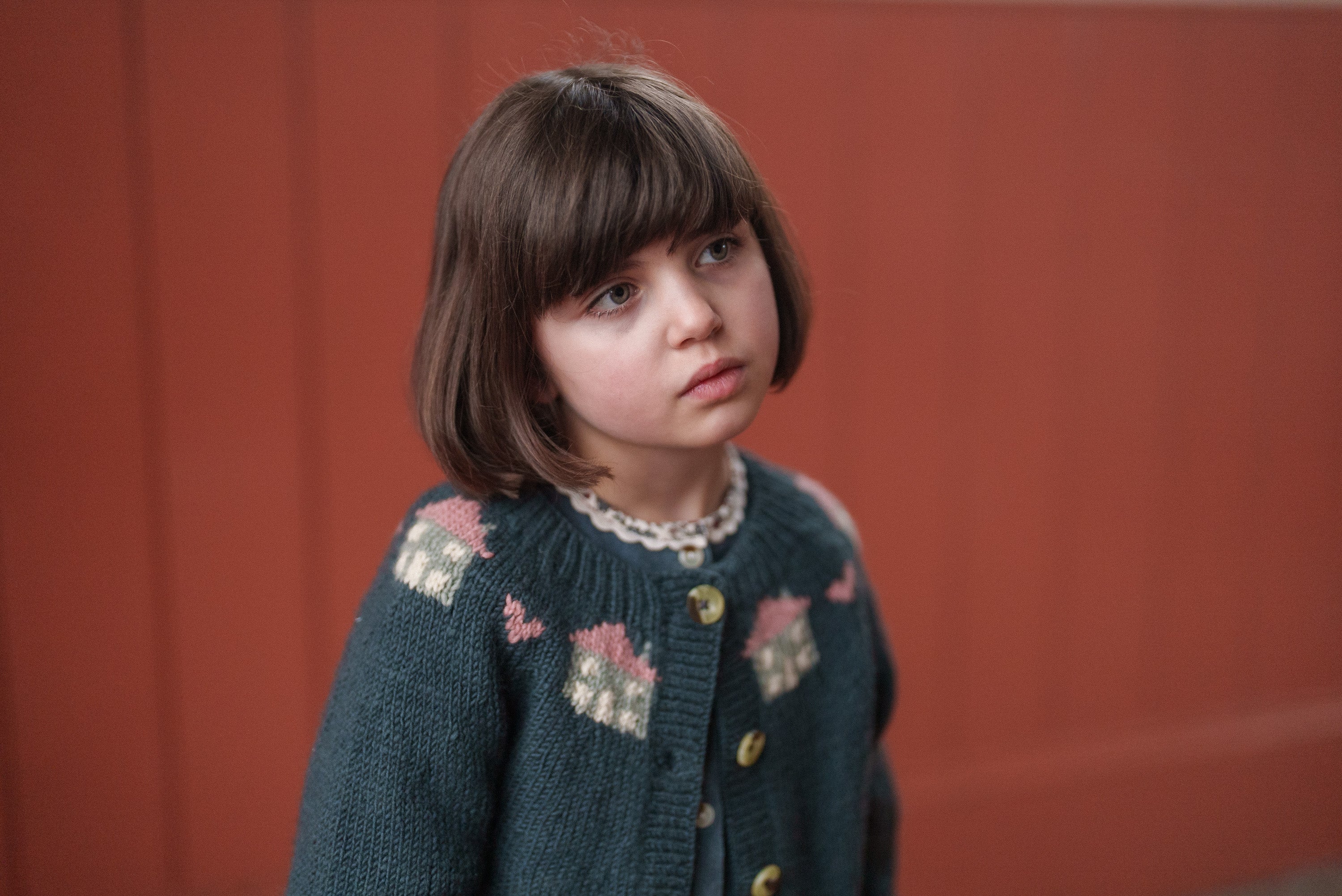 Young girl wearing a hand-knitted multicolor blue merino cardigan, showcasing vintage style sustainable children’s clothing designed with natural materials.