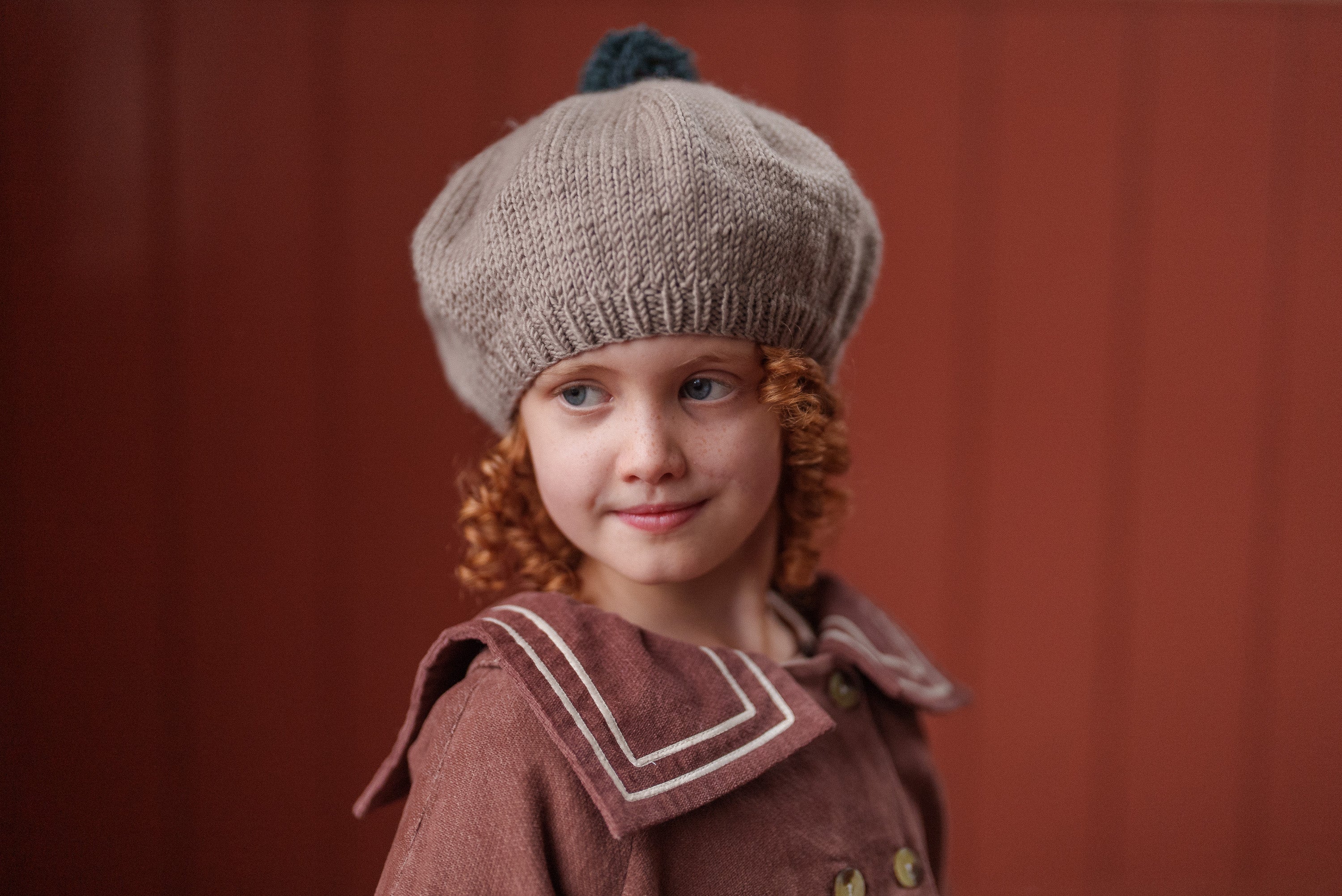 Young girl wearing a vintage style hand-knitted merino beret in oat color, showcasing sustainable and ethically made children’s clothing with a natural, organic feel.