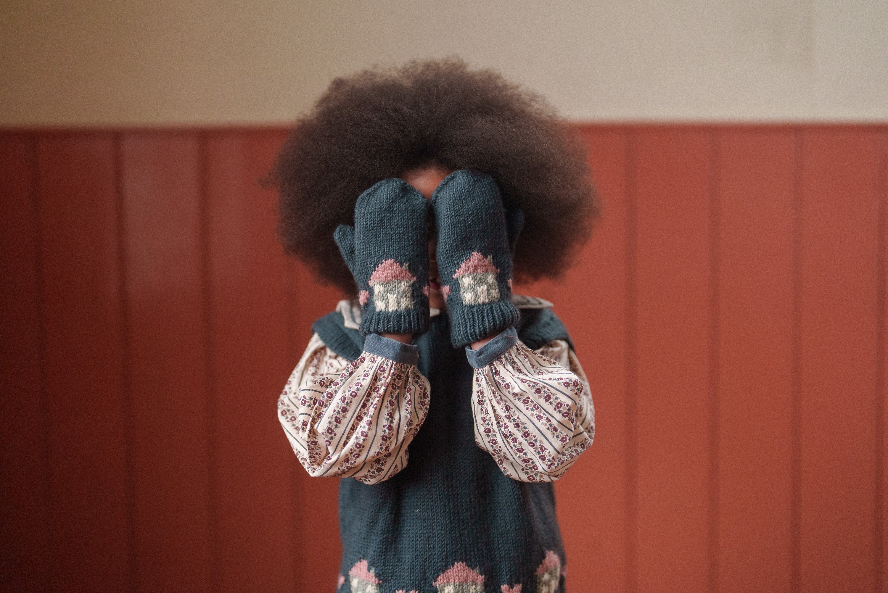 Child wearing vintage style girls blouse in organic cotton with floral patterns and blue knit mittens, showcasing ethical and sustainable children's clothing.