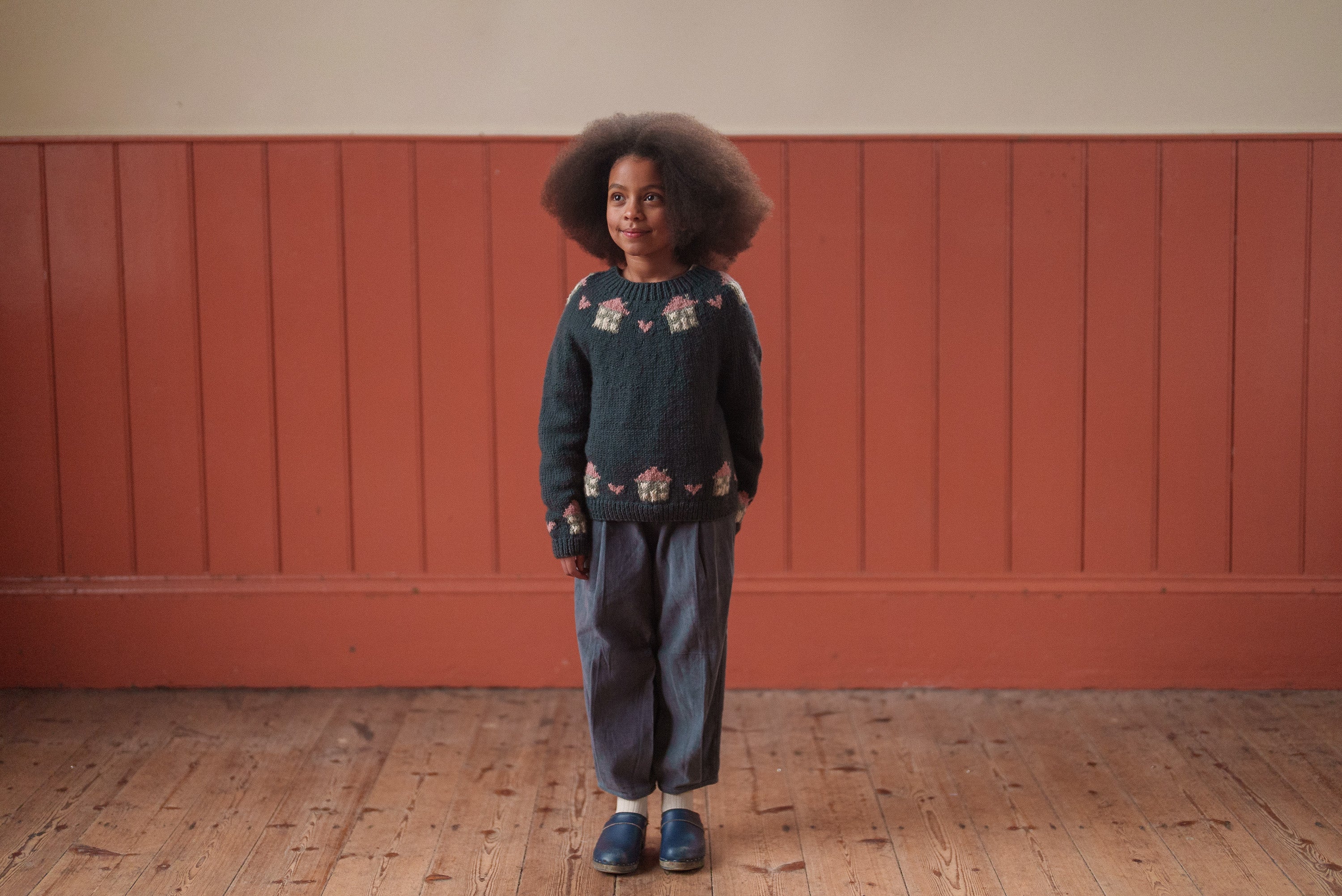 Child wearing vintage-style children’s clothing in organic cotton and velvet, featuring blue tones in a warm, natural setting reflecting sustainable and ethical fashion.