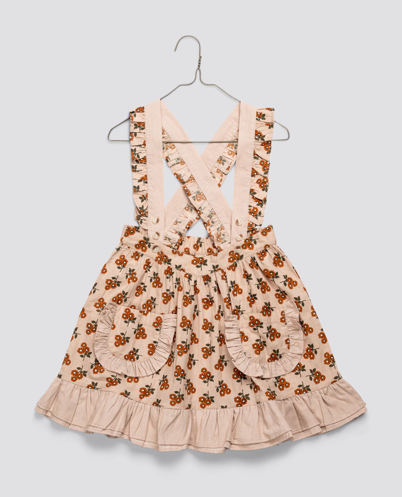 Vintage style girls skirt with marigold floral pattern in organic cotton, featuring ruffled pockets and adjustable crisscross straps for sustainable children's clothing.