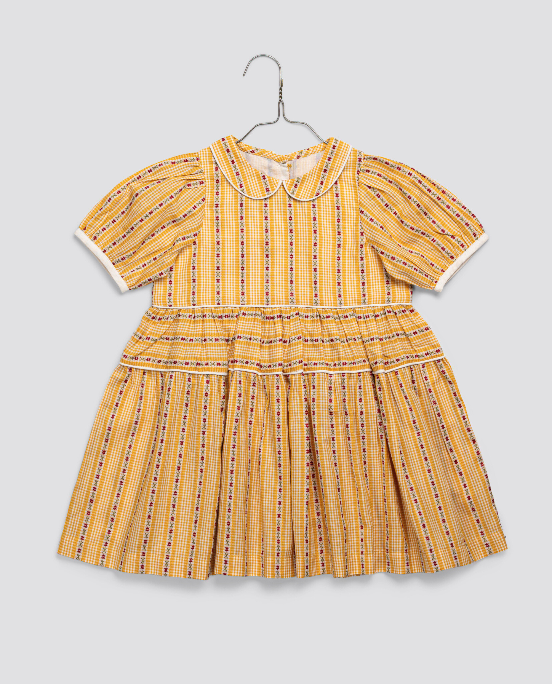 Vintage-style girls dress in yellow floral organic cotton with a classic collar and short puff sleeves, designed for sustainable and ethical kids clothing.