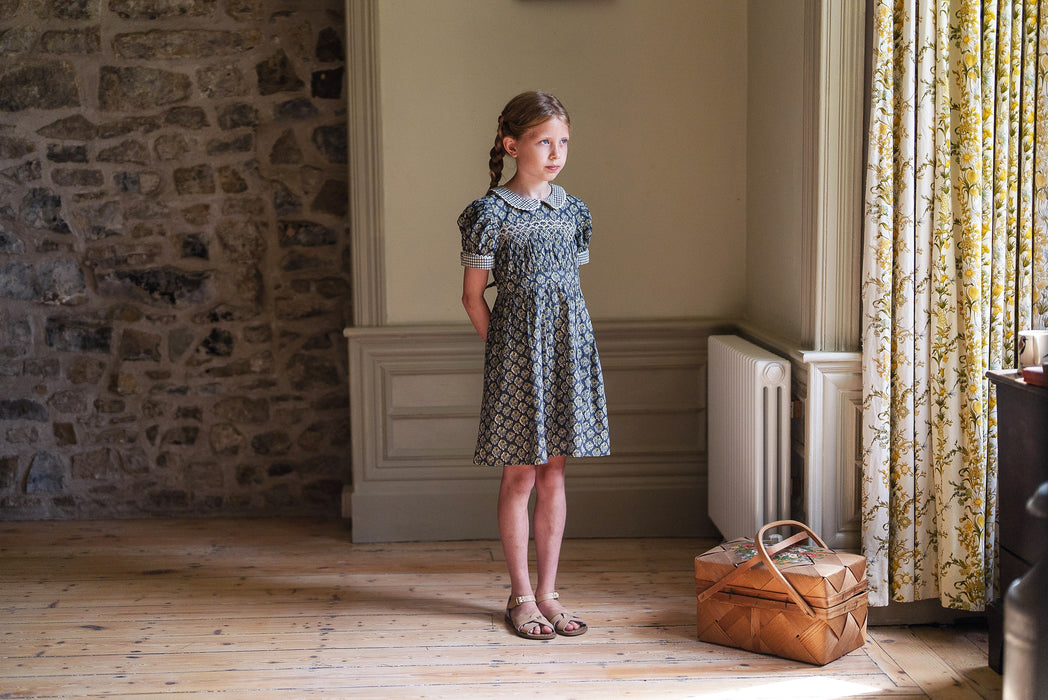 Our timeless, vintage inspired Orla Dress has been made in our organic cotton thistle floral fabric. This pretty children's dress is perfect for special occasions or everyday wear. It has beautiful hand smocking over a gathered bodice, full, puffed sleeves with contrasting cuffs and a contrasting Peter Pan collar. Designed for comfort and style, the full skirt allows for easy movement, it's sure to become a favourite for little girls and looks so sweet with little vintage style leather sandals. 
