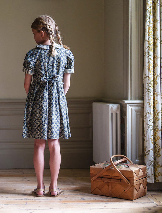 Our timeless, vintage inspired Orla Dress has been made in our organic cotton thistle floral fabric. This pretty children's dress is perfect for special occasions or everyday wear. It has beautiful hand smocking over a gathered bodice, full, puffed sleeves with contrasting cuffs and a contrasting Peter Pan collar. Designed for comfort and style, the full skirt allows for easy movement and the tie up back gives a lovely silhouette. 