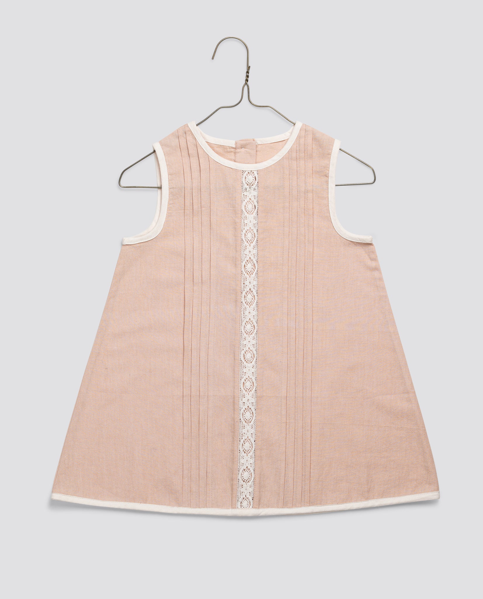 Sleeveless vintage-style girls dress in soft powder pink organic cotton with delicate lace trim and pintuck details, crafted ethically with natural materials.