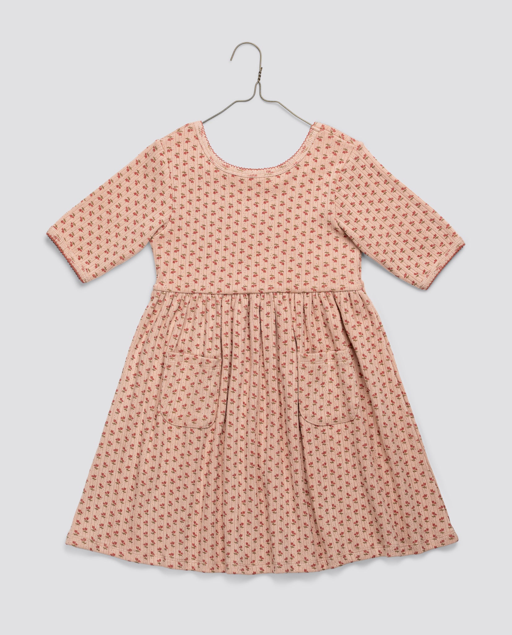 Pink floral vintage style girls dress made from organic jersey cotton, featuring a soft pointelle texture with long sleeves and front pockets, ethically made and sustainable.