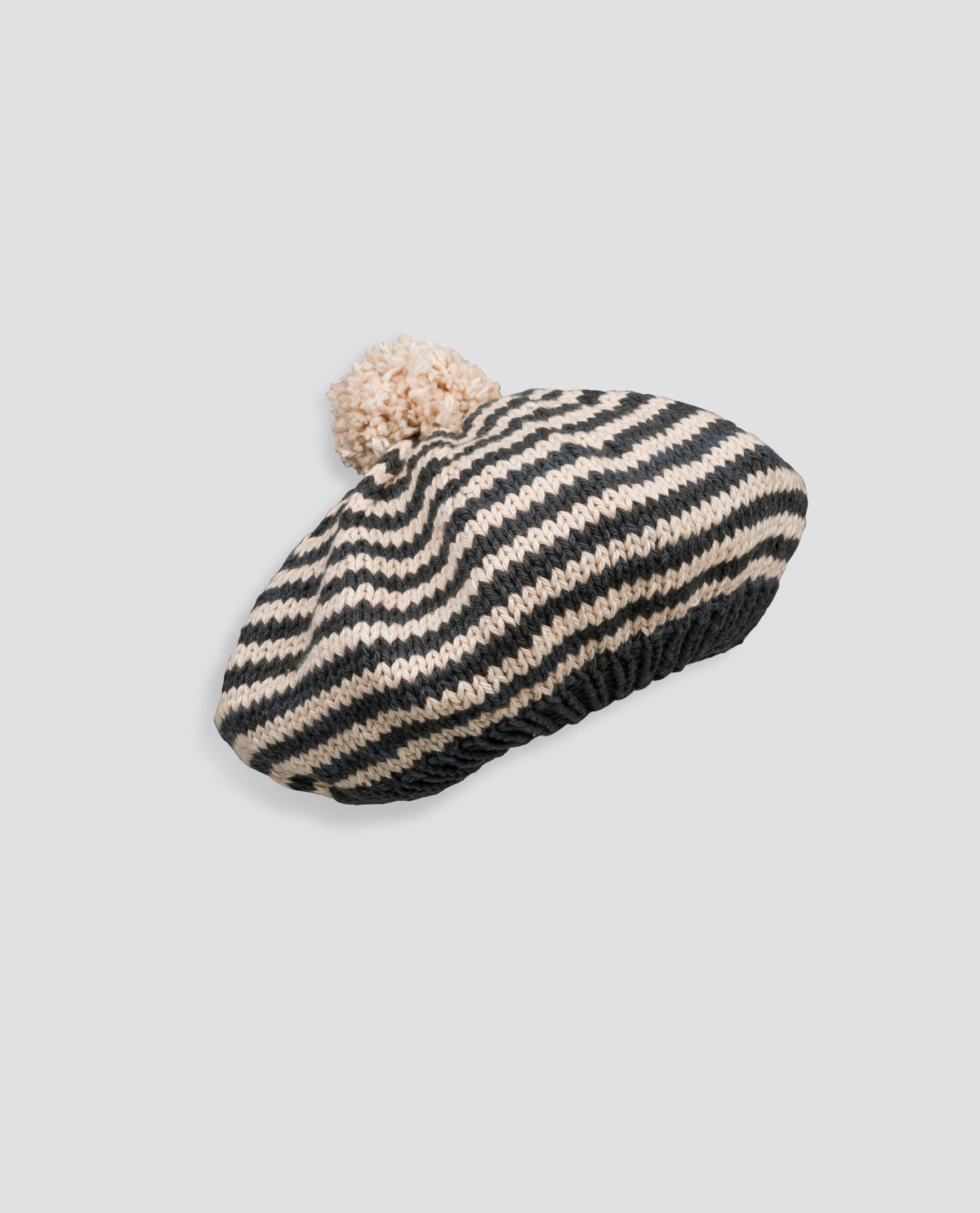 Hand-knitted beret featuring a striped pattern and soft pompom, ethically made for sustainable children's accessories.