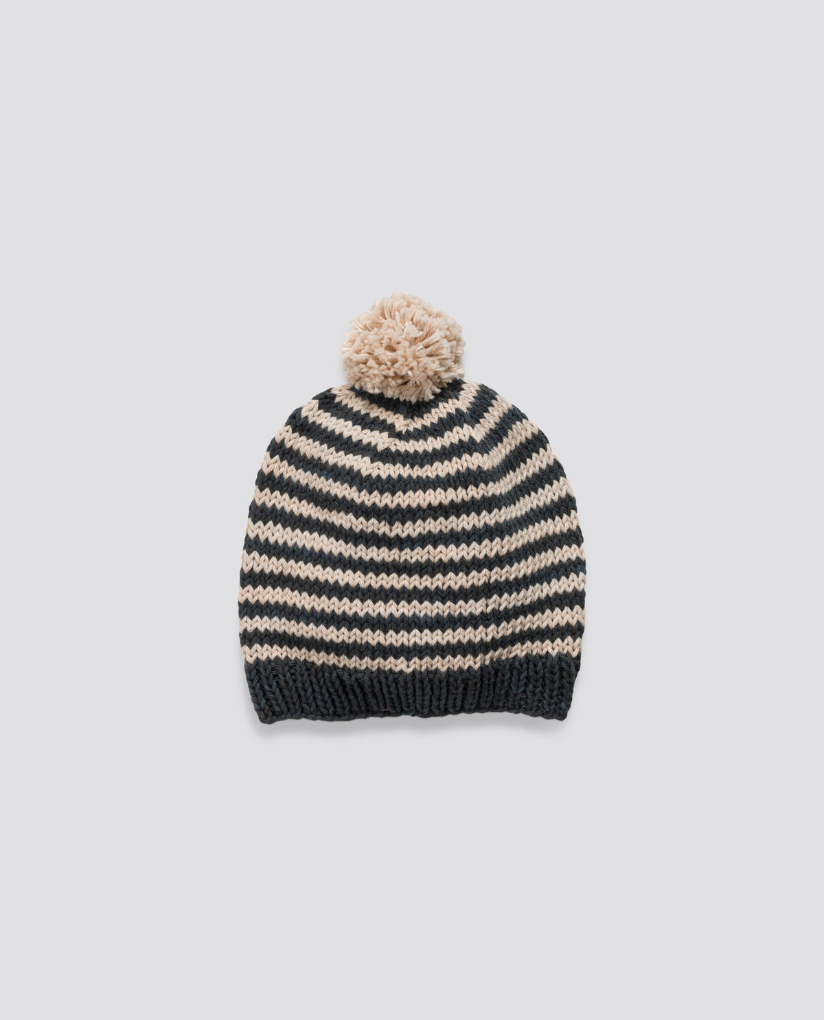 Hand-knitted black and cream striped bobble hat, crafted with care and ethically made for sustainable kid's accessories.