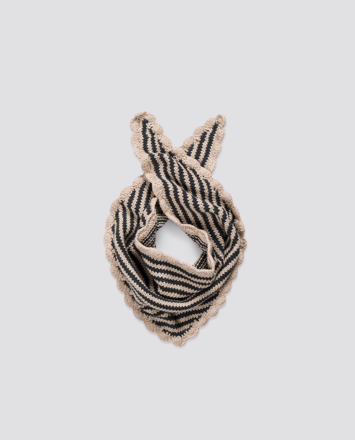 Vintage-inspired children's scarf, hand knitted with a black and cream stripe design and scalloped edging, reflecting ethical and sustainable values.