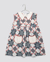 Girls vintage-style dress in blue and floral geometric patchwork with a white collar and pockets, made from organic cotton blend for sustainable kids clothing.