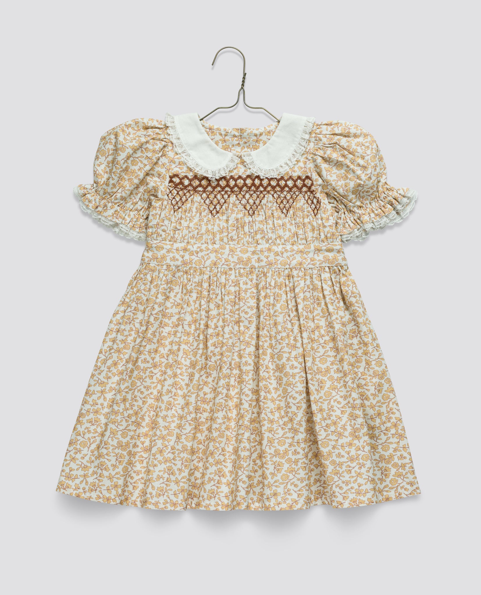 Vintage style floral cotton blend dress for toddlers and kids with puff sleeves, white Peter Pan collar, and delicate smocked detailing in warm earthy tones.