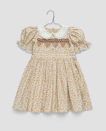 yellow floral dress with lace details on a hanger against a light grey background