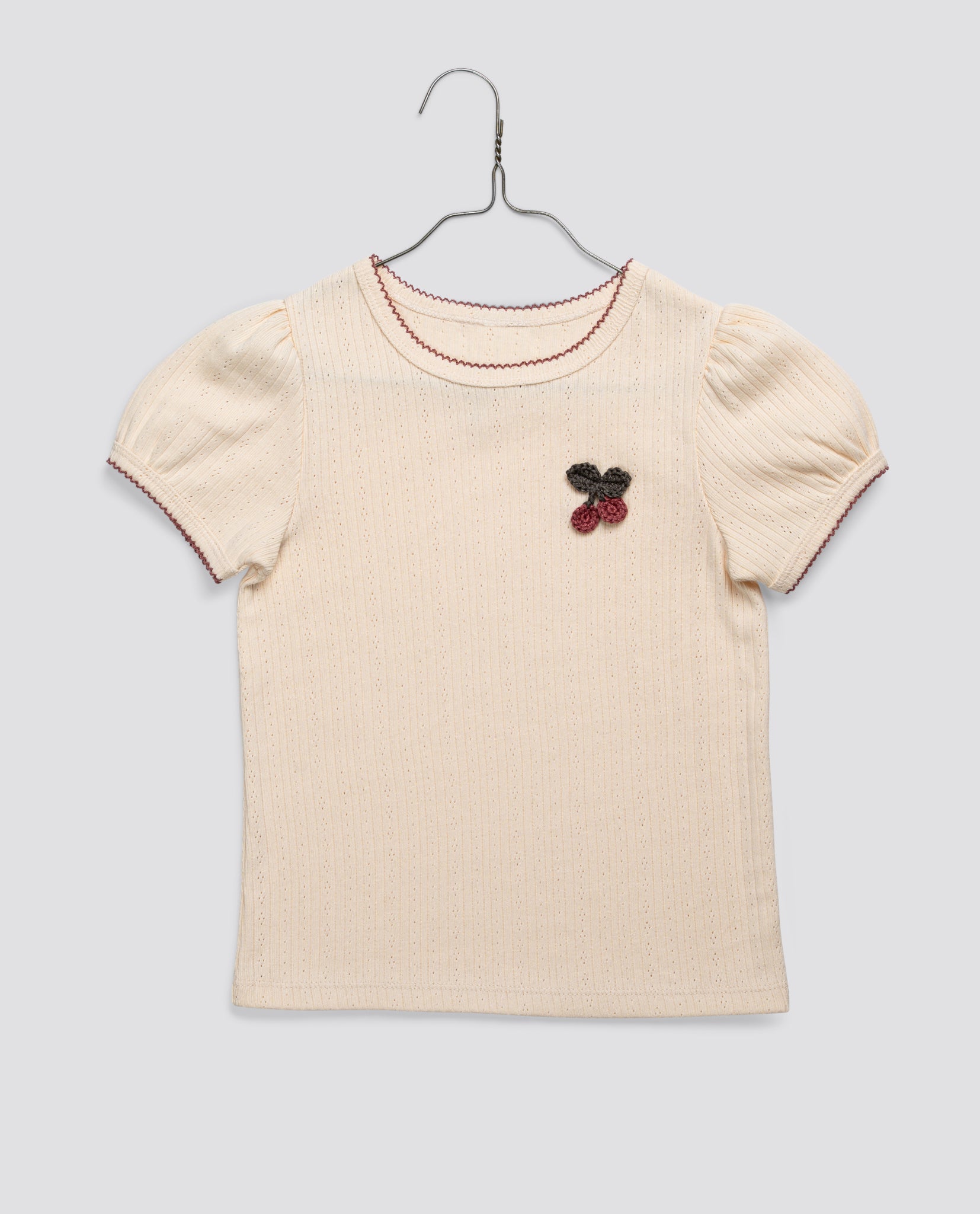 Cream organic jersey cotton toddler t-shirt with delicate crochet cherry detail, puff sleeves, and vintage-inspired stitching, made with sustainable, natural materials.