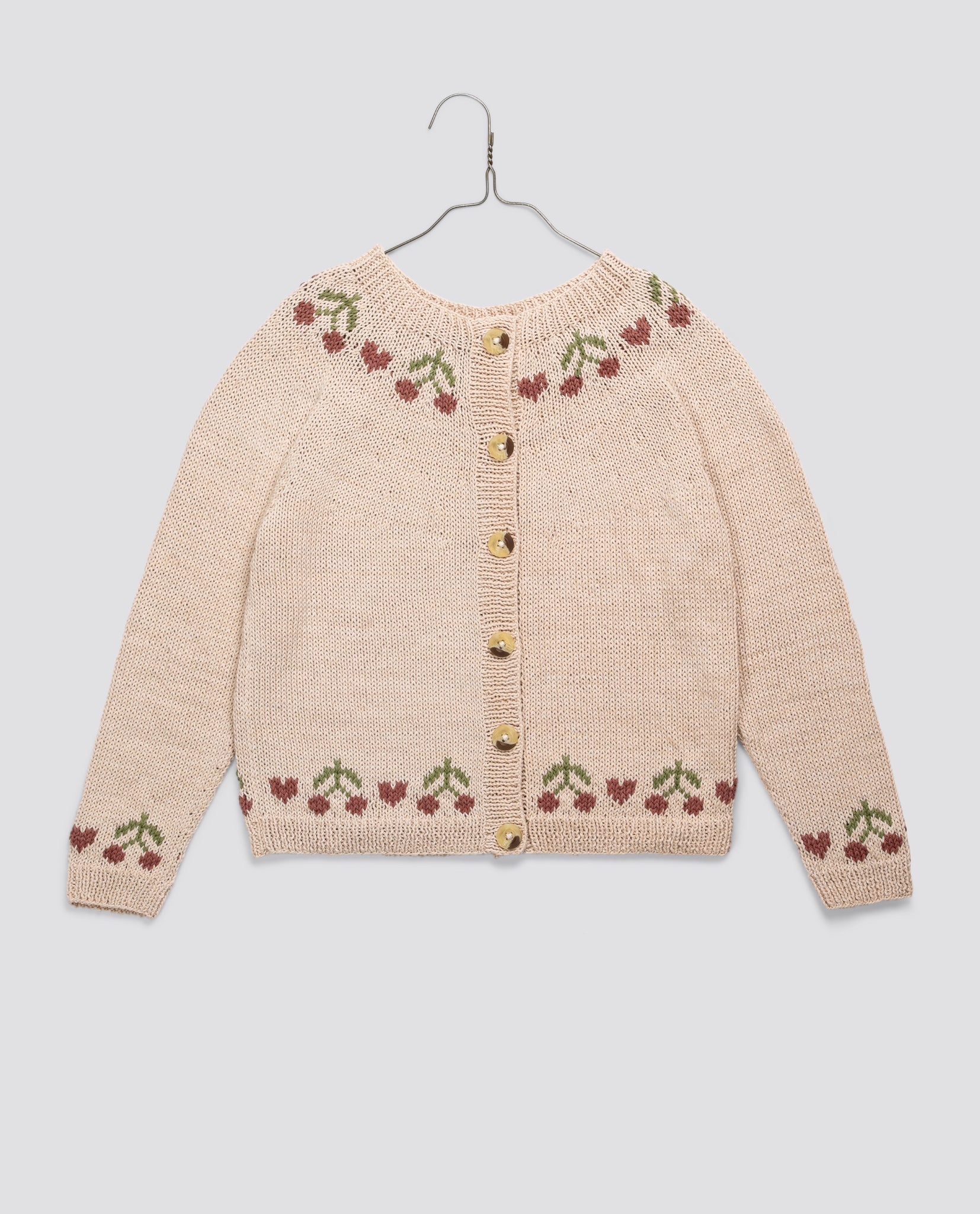 Cream hand-knitted children's cardigan with cherry pattern details in soft cotton, featuring vintage style and sustainable, ethically made design for girls.