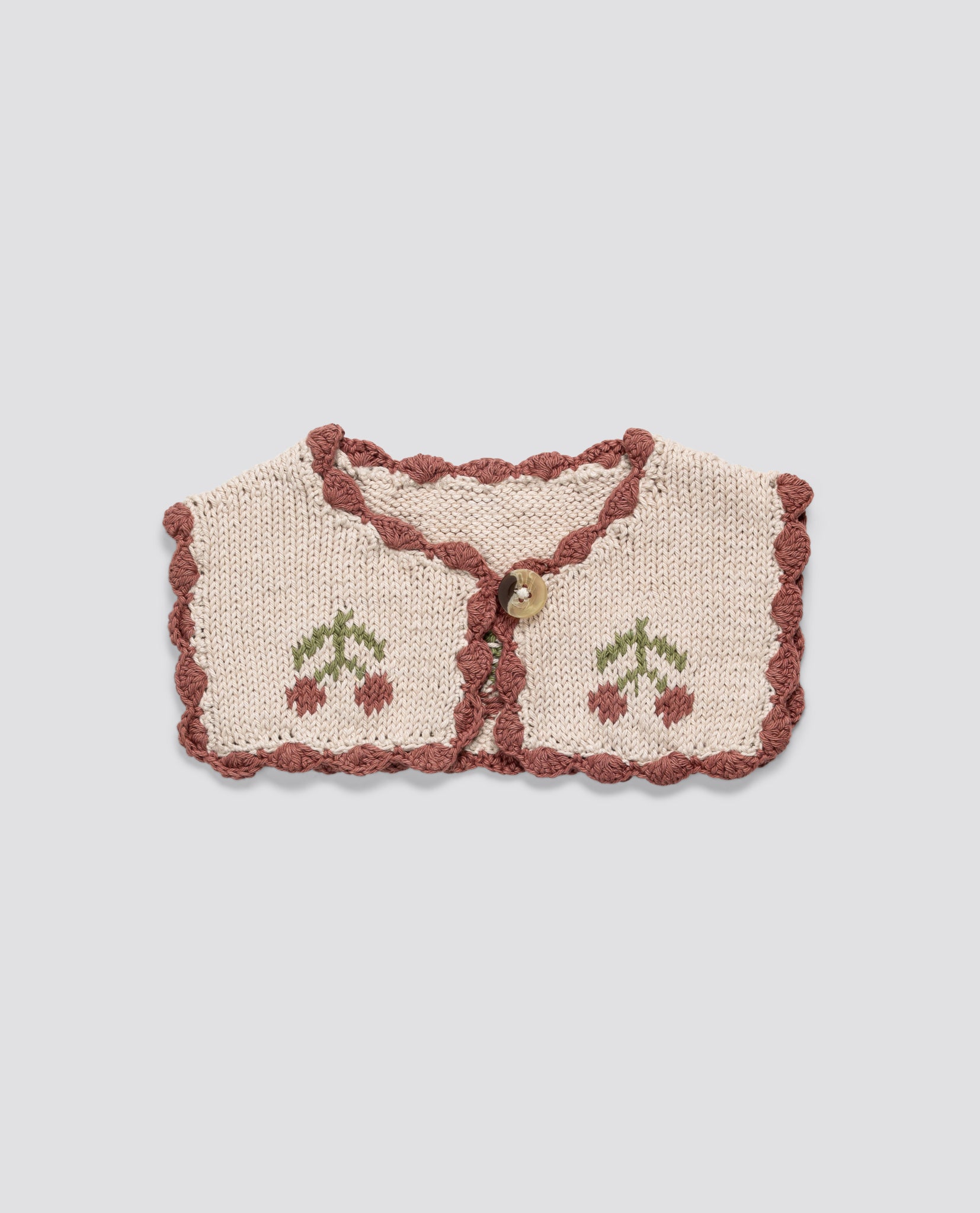 Hand-knitted natural cotton collar for children with vintage cherry design and scalloped edges in soft organic yarn, reflecting ethical, sustainable style.