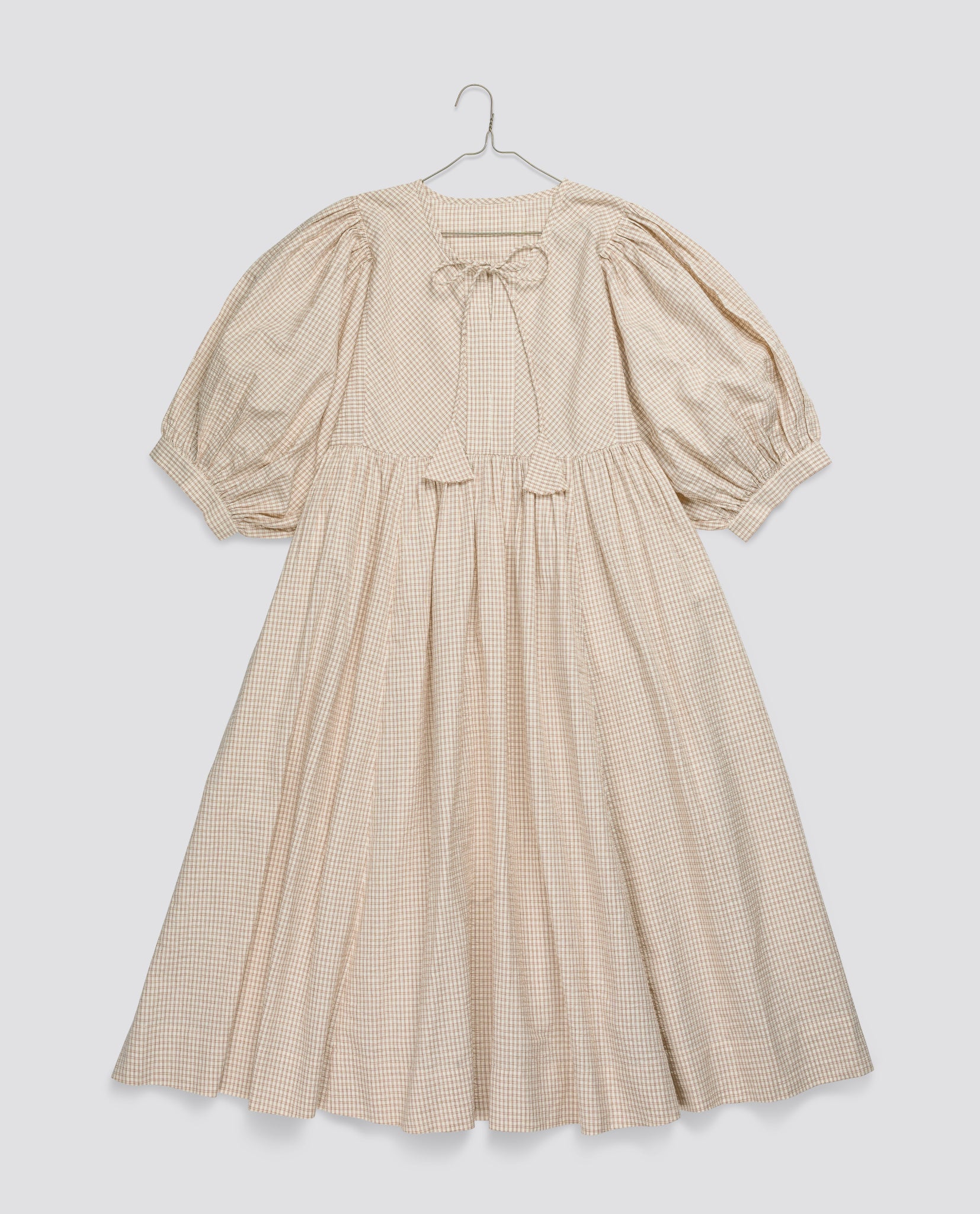 Vintage style girls dress in soft straw check pattern with puffed sleeves and delicate tie at the neckline, made from organic cotton for sustainable children's clothing.