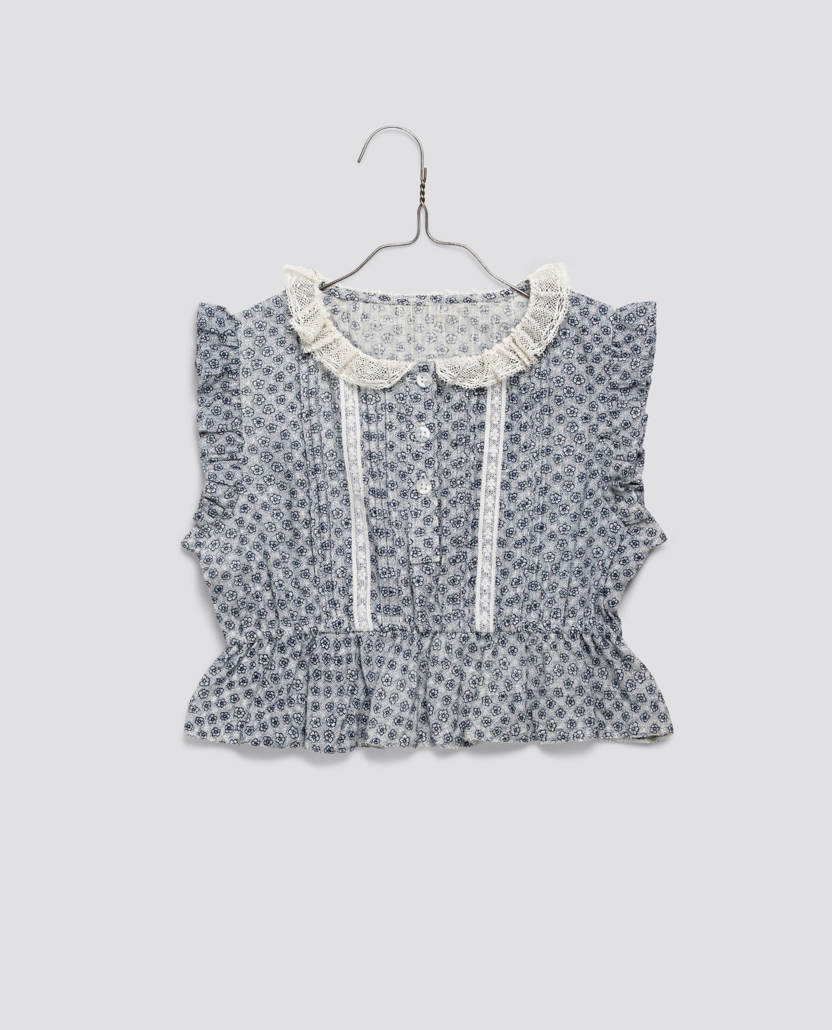 Girls vintage style blouse in soft organic cotton with delicate floral print, lace trim, and ruffled collar, designed with care for sustainable childhood fashion.