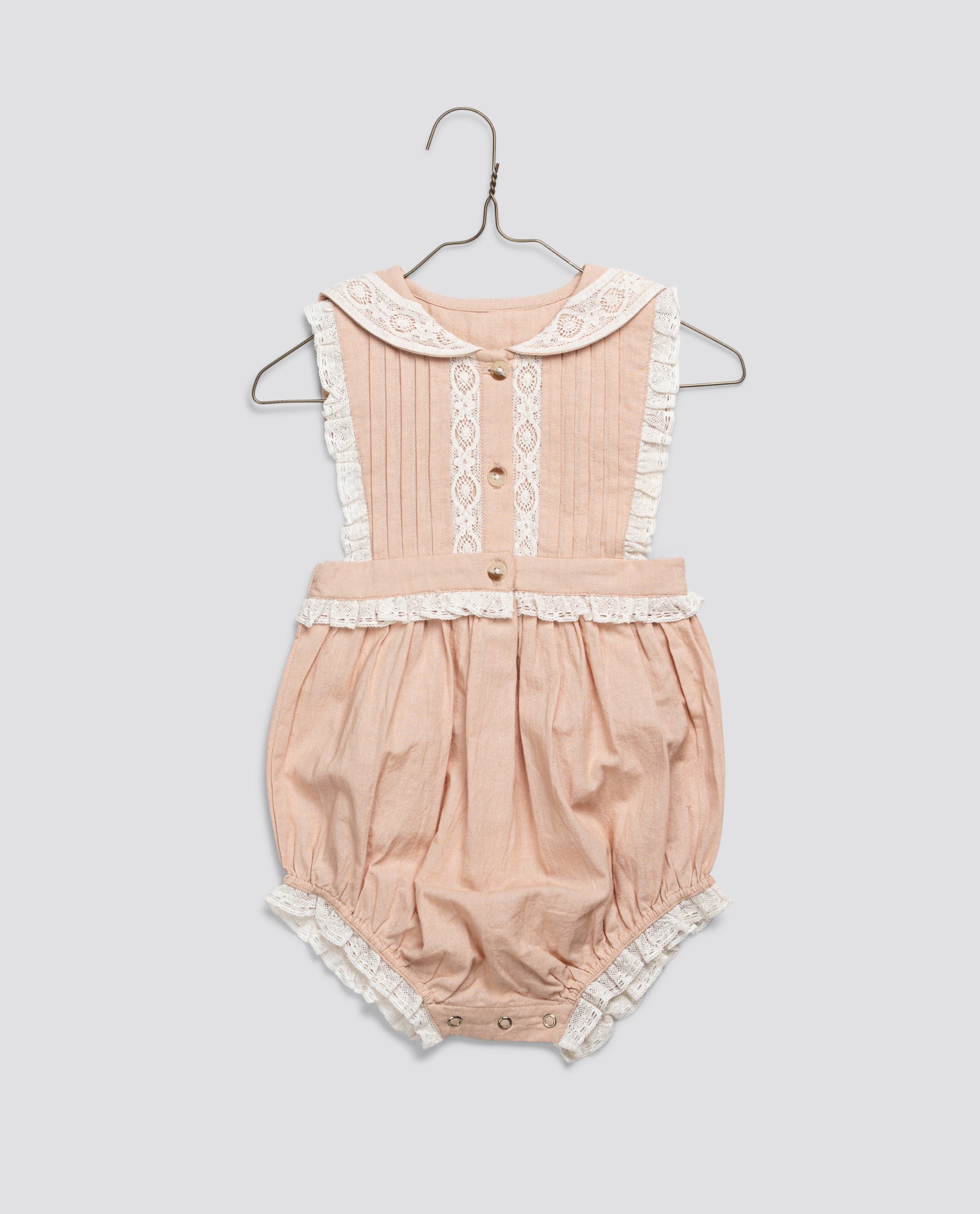 Vintage style baby romper in soft powder pink organic cotton with delicate lace trim, designed for comfort and sustainability in children's clothing.