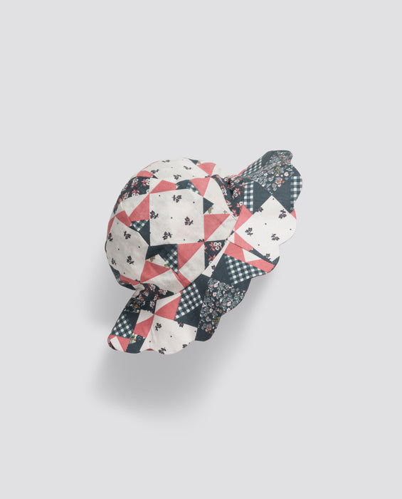 Scalloped patchwork baby hat made from organic cotton featuring vintage-inspired floral and check patterns in soft pink, navy, and cream tones.