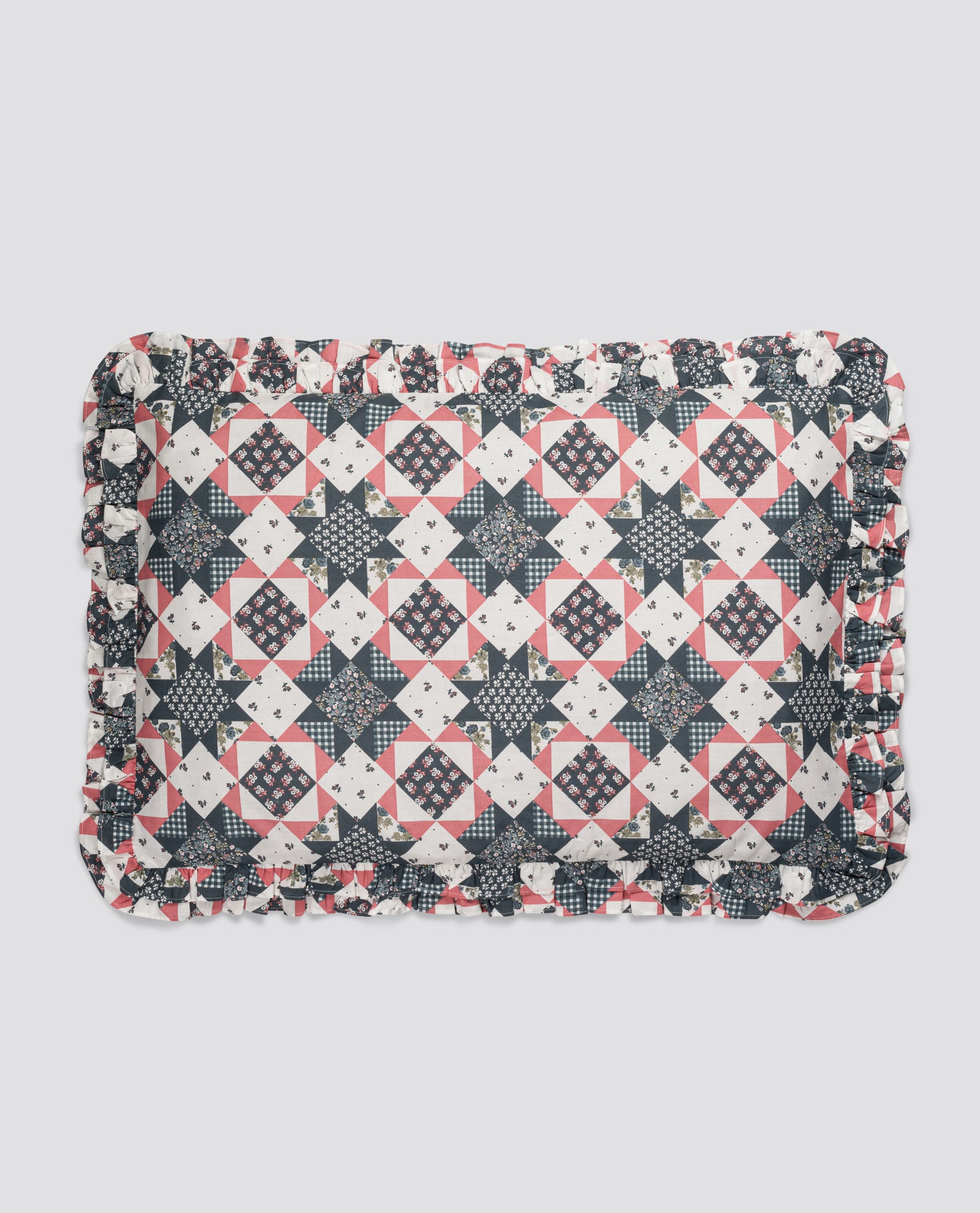 Vintage style patchwork pillowcase with floral and geometric patterns in muted navy and soft pink, made from organic cotton with a ruffled edge for a natural, delicate touch.