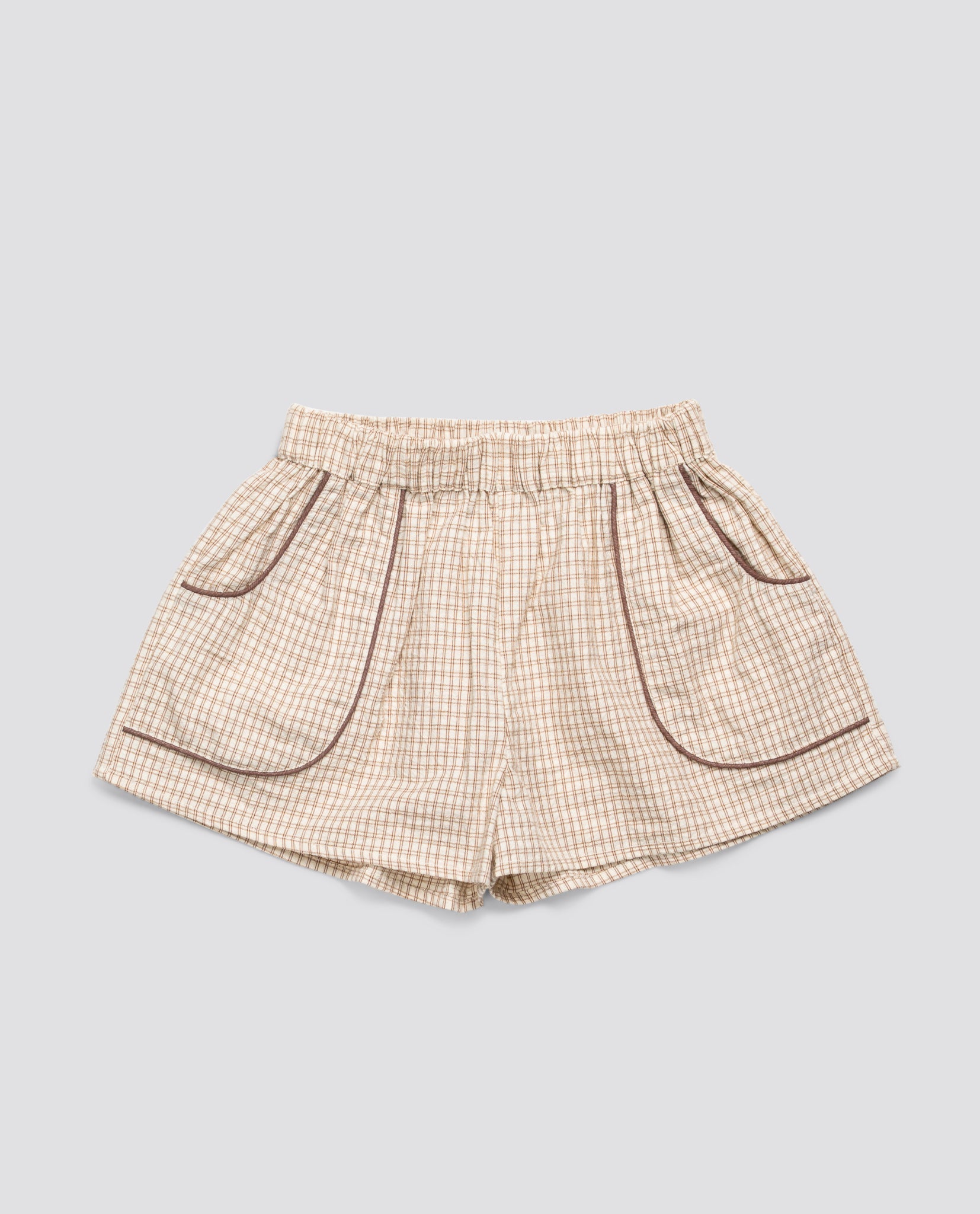 Light beige vintage-style checkered shorts for children made from organic cotton with contrasting trim and elastic waistband, designed for sustainable, ethical kids' clothing.