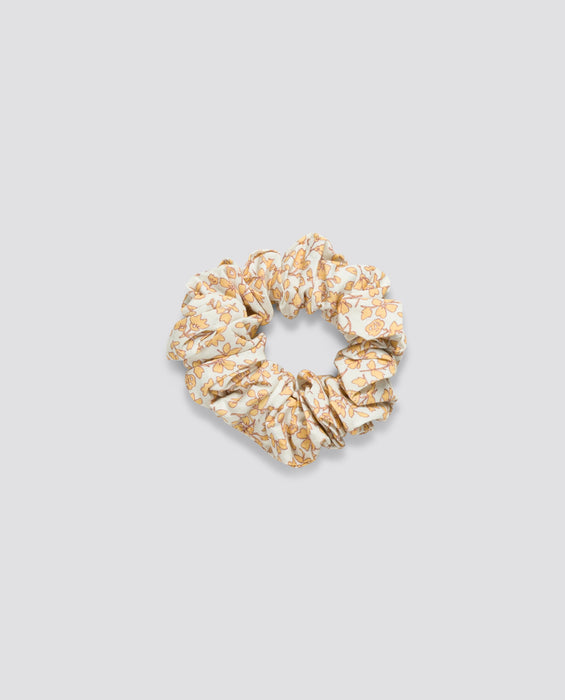 Soft fabric scrunchie in a delicate vintage floral pattern with natural tones, made from organic cotton for gentle, sustainable style in children's accessories.