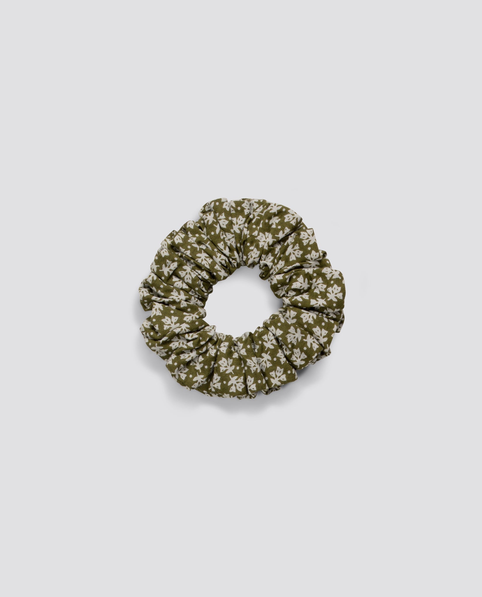 Olive green scrunchie with a delicate white floral pattern, made from organic natural fabric, reflecting a vintage and sustainable style for children.