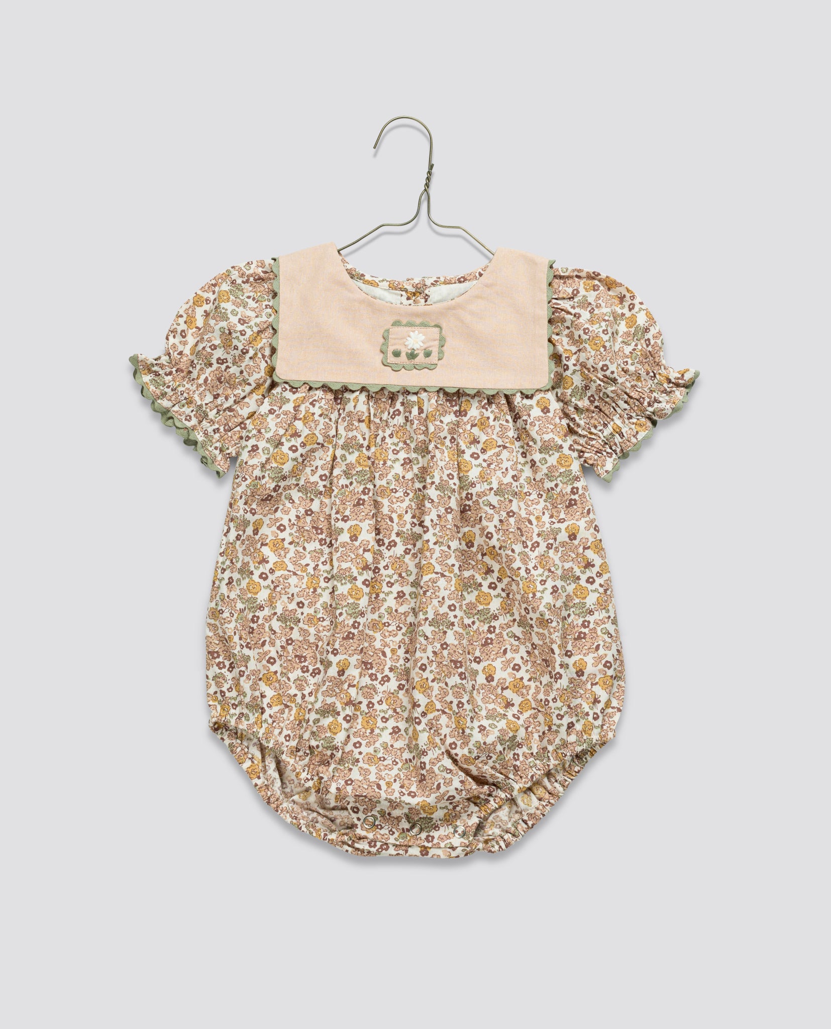 Vintage style baby romper in soft organic cotton with delicate floral pattern and puffed sleeves, designed for gentle comfort and sustainable children's clothing.