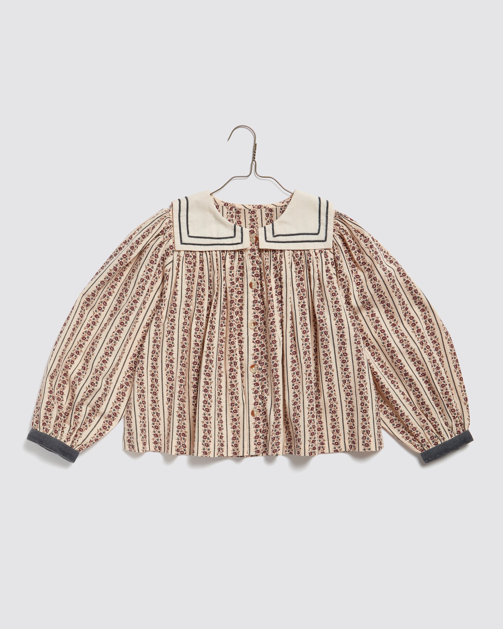 Vintage style girls blouse with delicate floral stripes, organic cotton fabric, traditional sailor collar, and gathered long sleeves for a sustainable, natural children's clothing look.