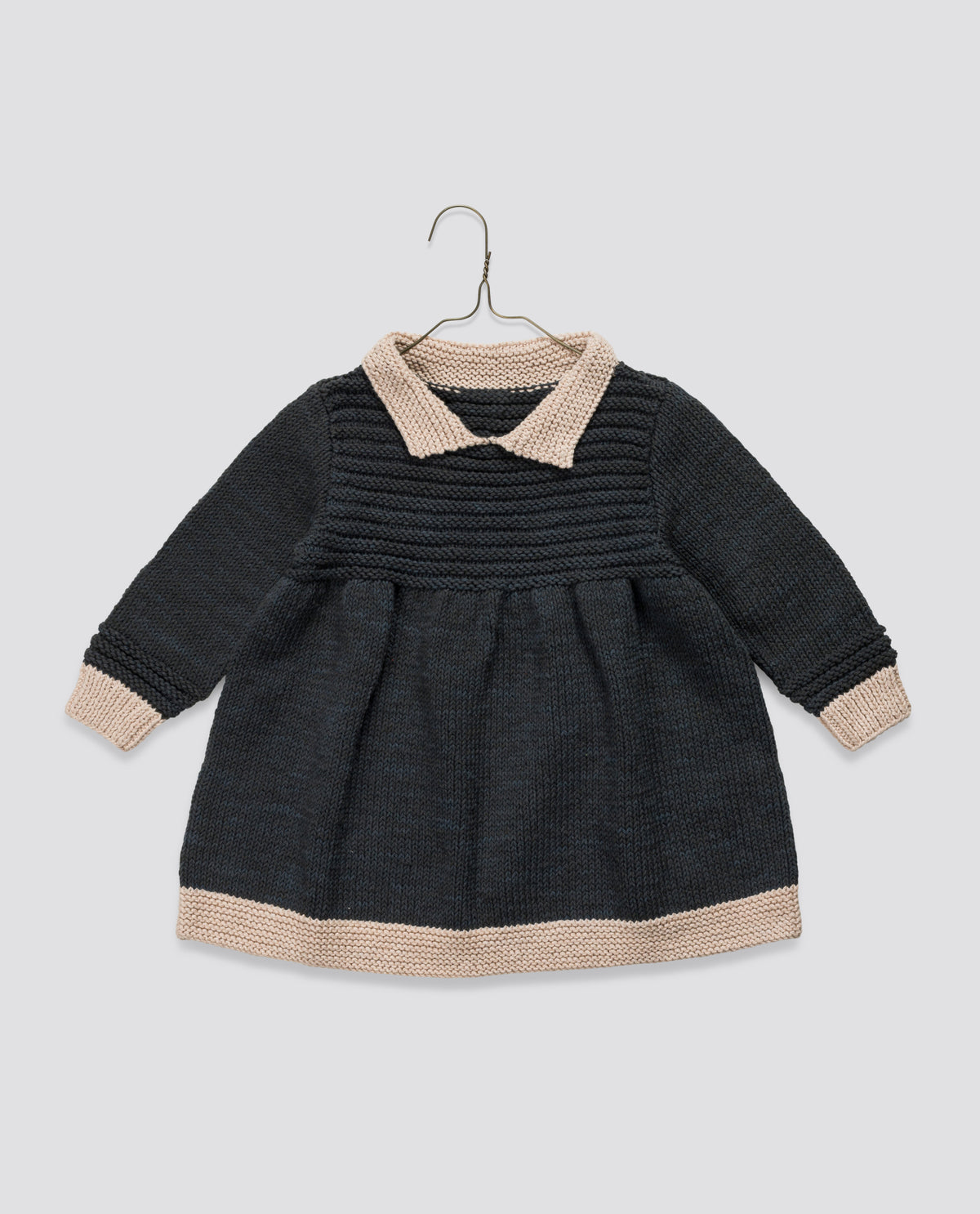 Timeless hand-knitted black and cream long sleeved dress in a vintage-inspired style, ethically made for children's sustainable fashion.