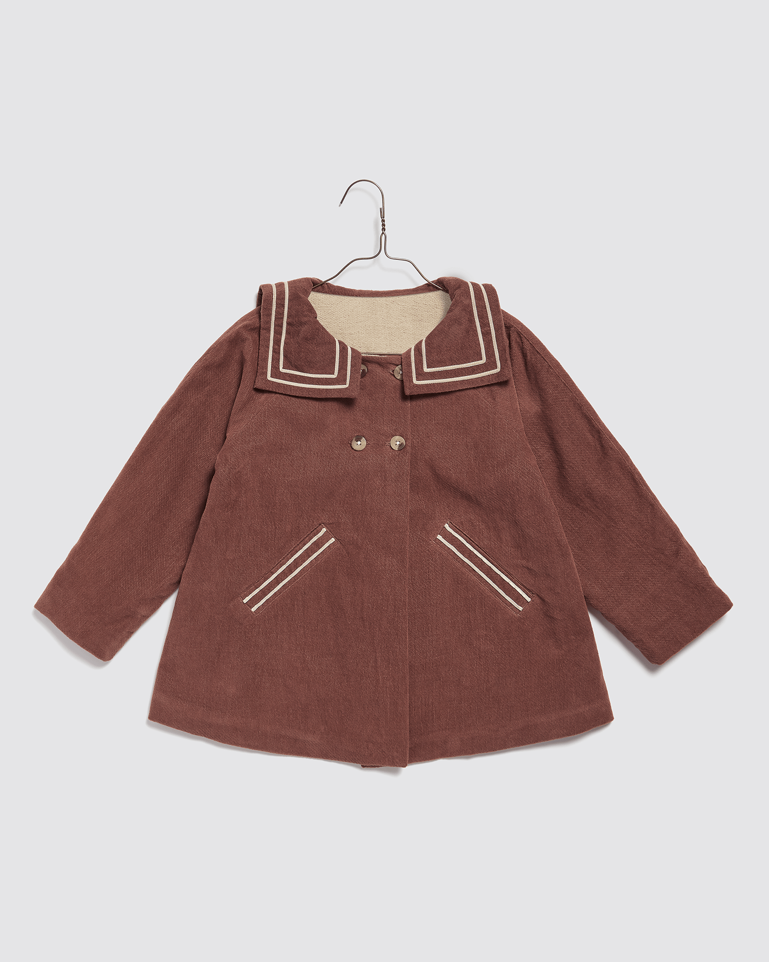 Vintage style girls' sailor coat in warm nutmeg velvet with natural organic fabric, featuring a traditional collar and stitched pocket details for sustainable children's clothing.