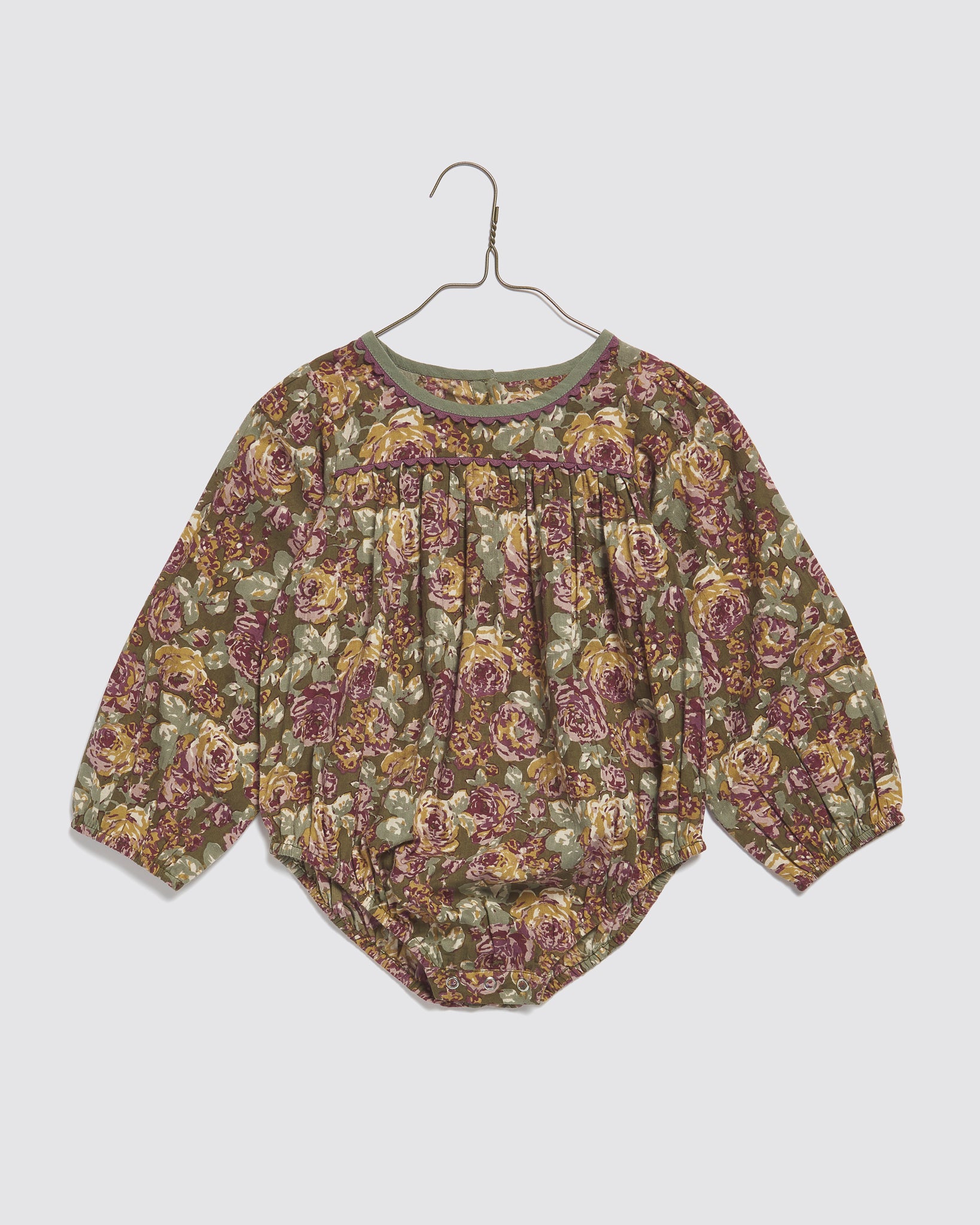 Vintage style baby romper with long sleeves in green, pink, and muted floral organic cotton, designed for comfort and sustainability in children's clothing.