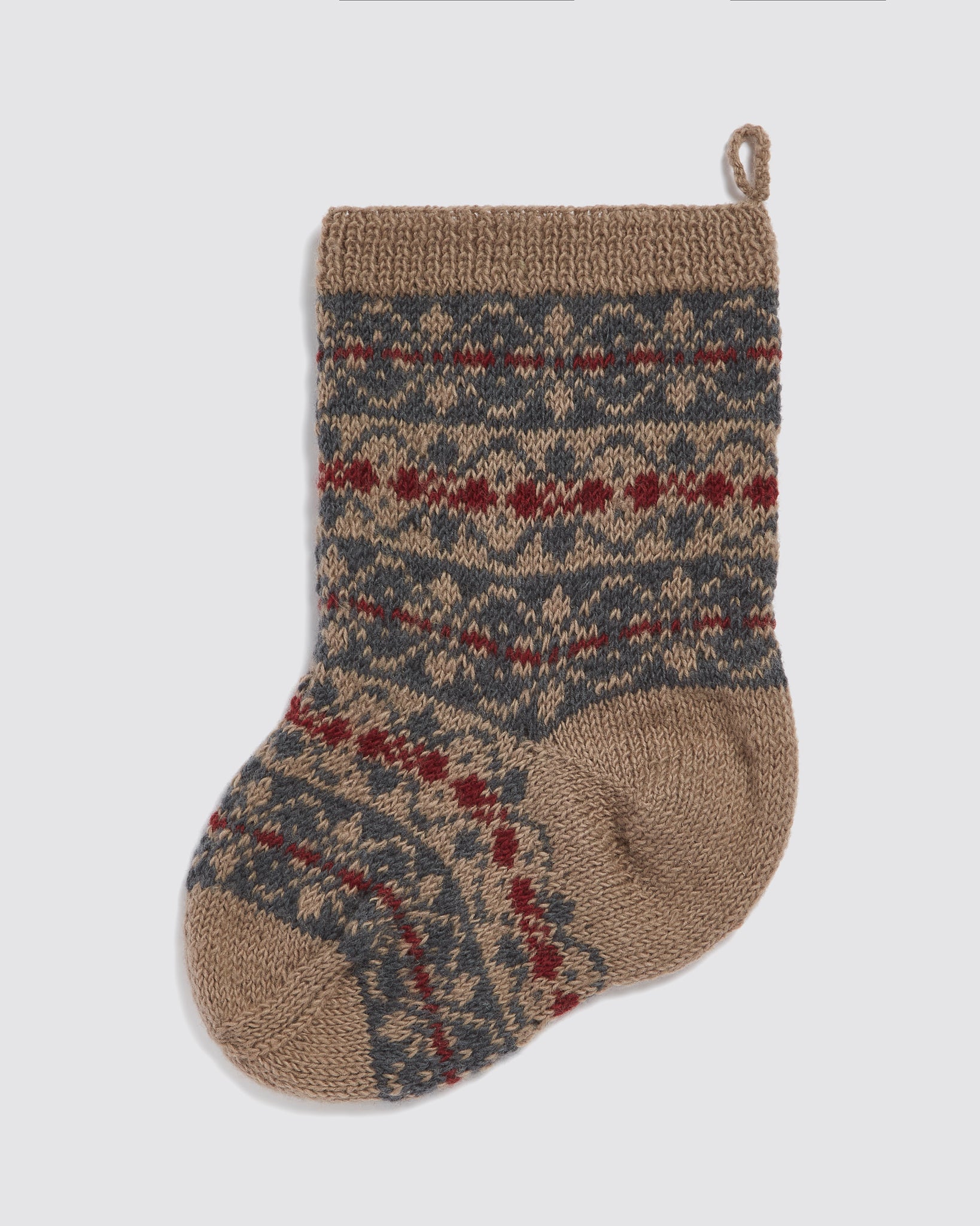 Hand-knitted stocking in natural merino wool featuring a vintage-inspired pattern in blue, beige, red, and cream, designed with care for an organic, sustainable holiday touch.