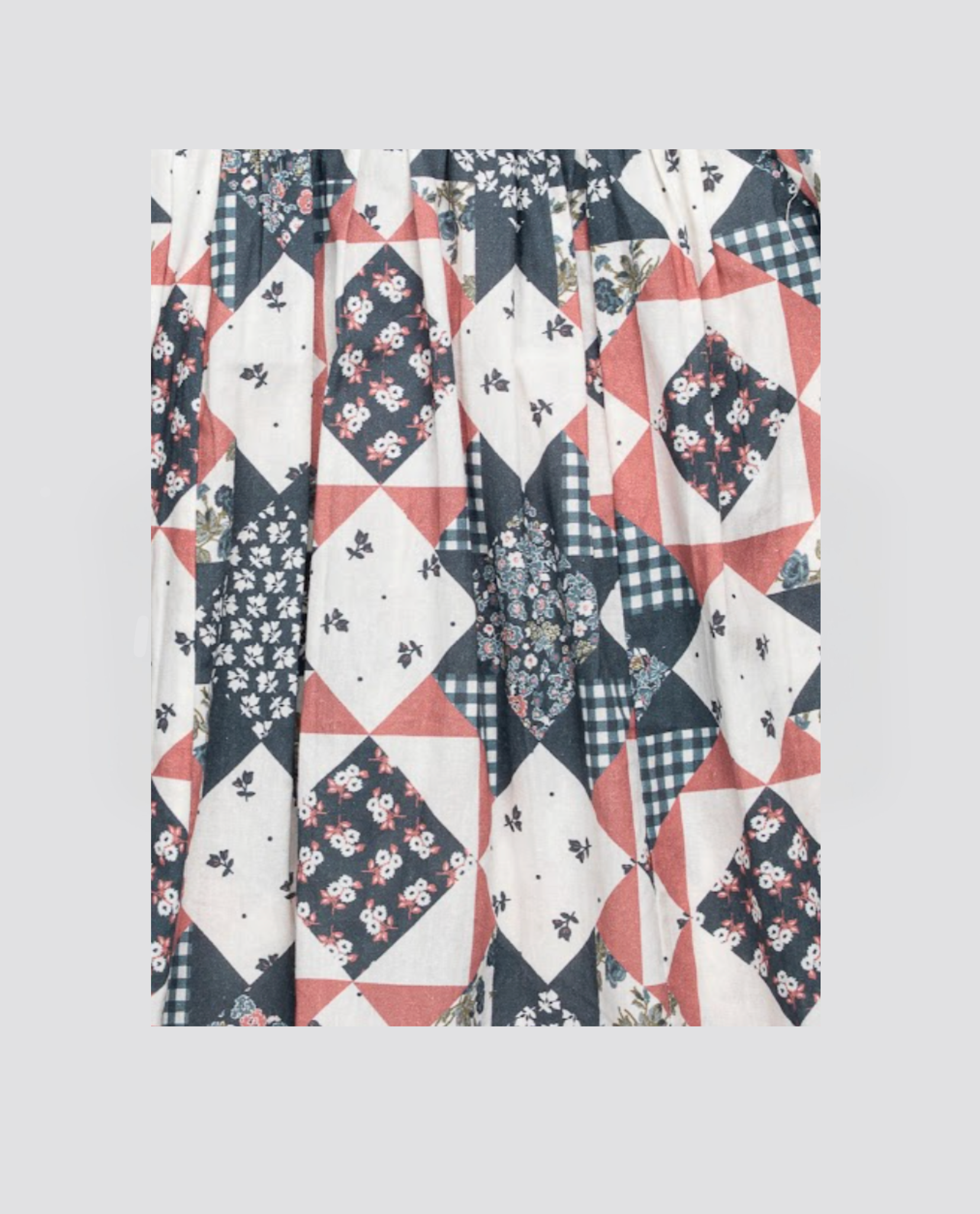 Close-up of organic cotton fabric with a patchwork floral pattern in blue and soft red tones, inspired by vintage style for children's clothing.