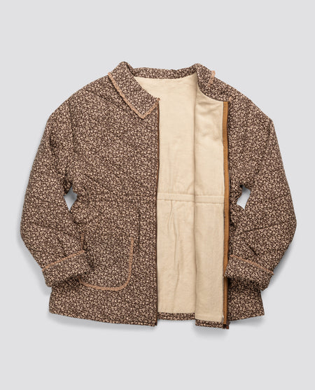 Ladies brown floral quilted jacket with zip front and elasticated waist. Collar with cotton trim and patch pockets with trim. Lined in soft jersey fabric. 