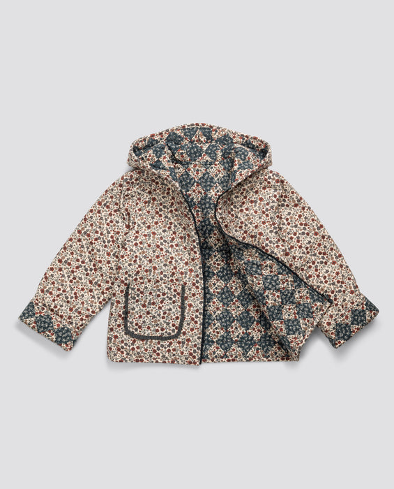 Children's reversible quilted hooded jacket in blue floral organic cotton prints. Zip up front, a generous hood and contrasting patch pockets. sustainably and ethically made