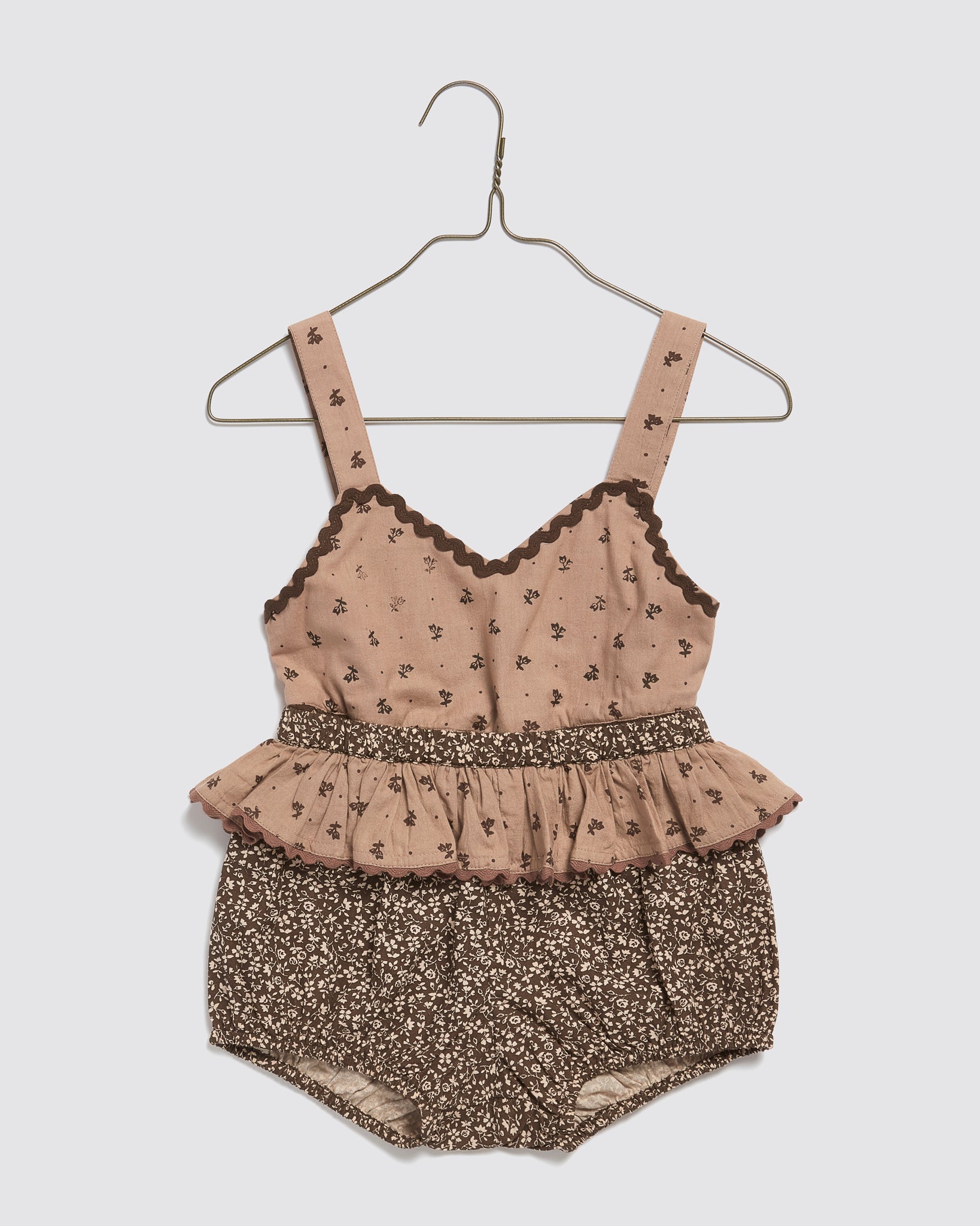 Brown and pink floral baby romper made from organic cotton, featuring vintage-inspired detailing with ruffled waist and wide shoulder straps, perfect sustainable kids clothing.