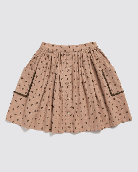 A full, gathered pink floral skirt made from 100% organic cotton fabric. This skirt has pockets with contrasting trim and has been ethically made.