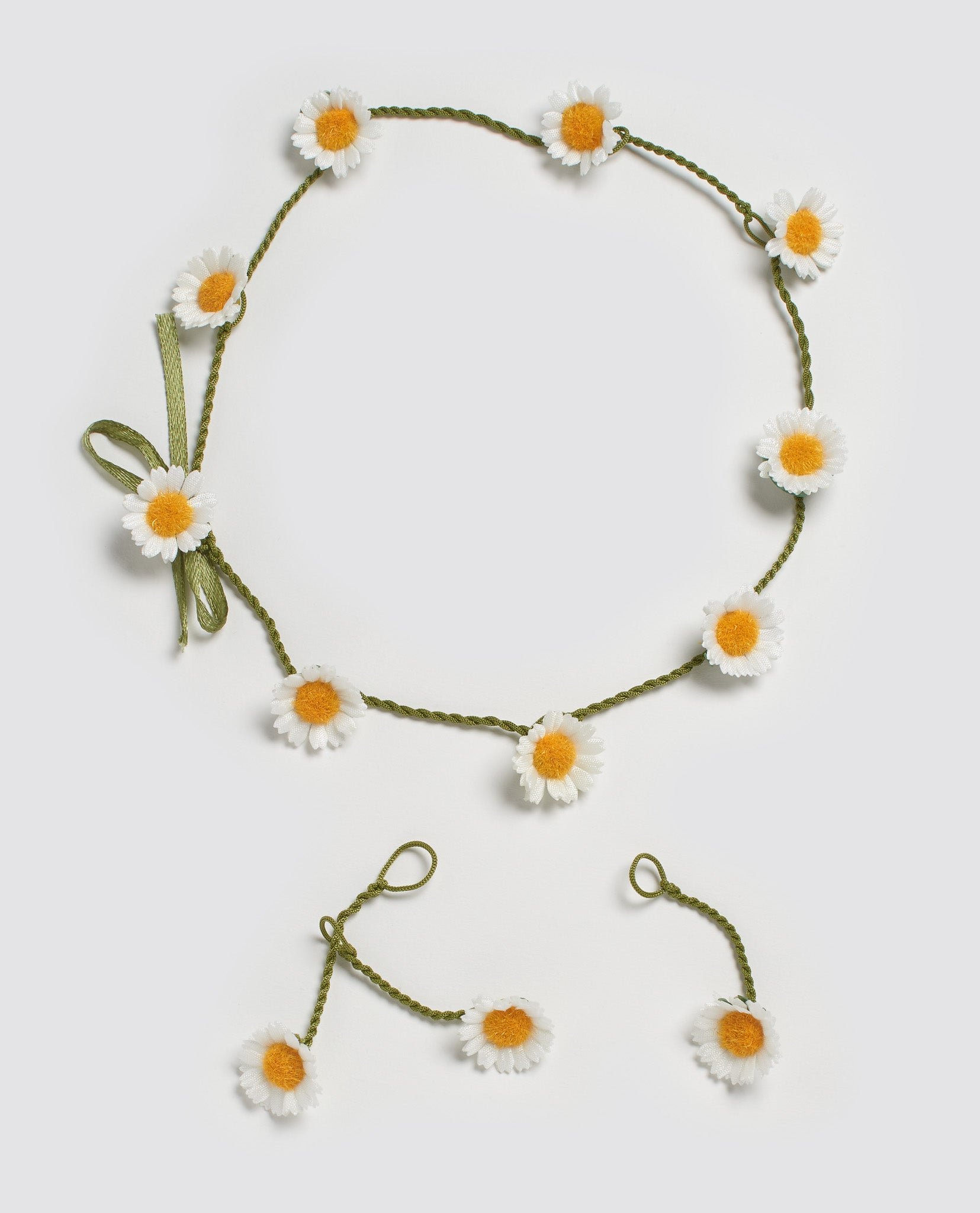 Delicate handmade daisy chain with soft white petals and yellow centers on green braided cord, evoking natural, vintage style for children’s accessories.